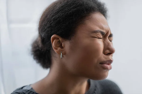 Triste mujer multirracial con crisis psicológicas llorando en casa - foto de stock