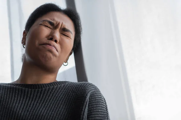 Vista de ángulo bajo de la joven mujer multirracial con depresión llorando en casa - foto de stock