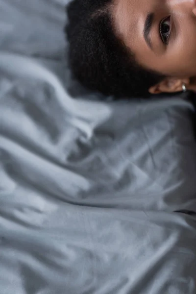 Vue recadrée de la femme multiraciale avec un problème mental couché sur le lit — Photo de stock