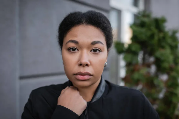 Retrato de mujer multirracial con depresión mirando a la cámara en la calle urbana - foto de stock