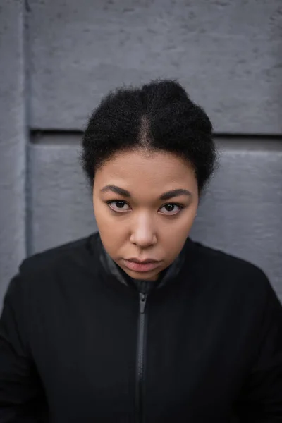 Porträt einer multirassischen Frau mit psychischen Problemen, die in der Nähe von Gebäuden im Freien in die Kamera schaut — Stockfoto