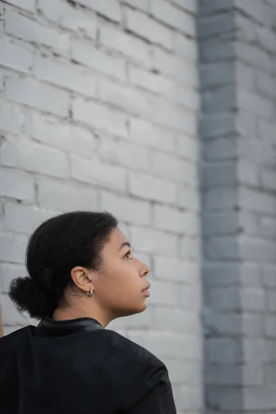 Side view of multiracial woman with psychological problem standing near brick wall — Stock Photo