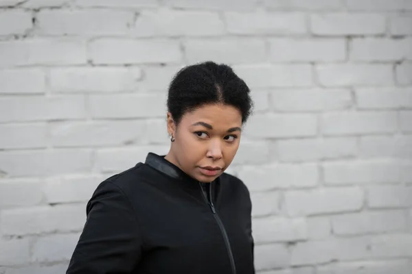 Femme multiraciale mécontente en veste regardant loin dans la rue urbaine — Photo de stock