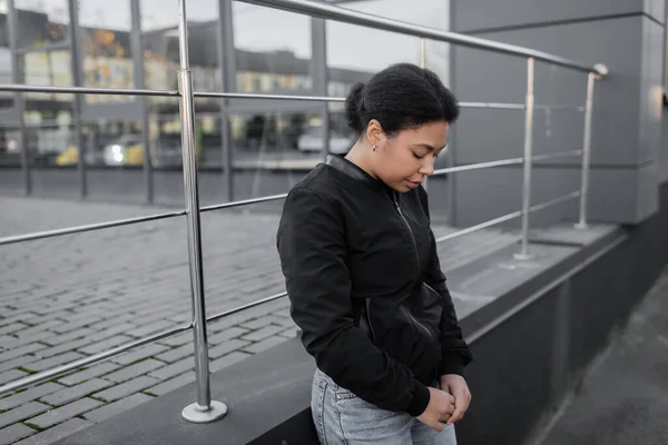 Jeune femme multiraciale avec apathie debout près du bâtiment à l'extérieur — Photo de stock