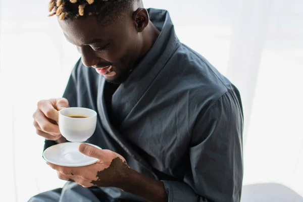Unbekümmerter afrikanisch-amerikanischer Mann mit Vitiligo, der zu Hause eine Tasse Kaffee hält — Stockfoto