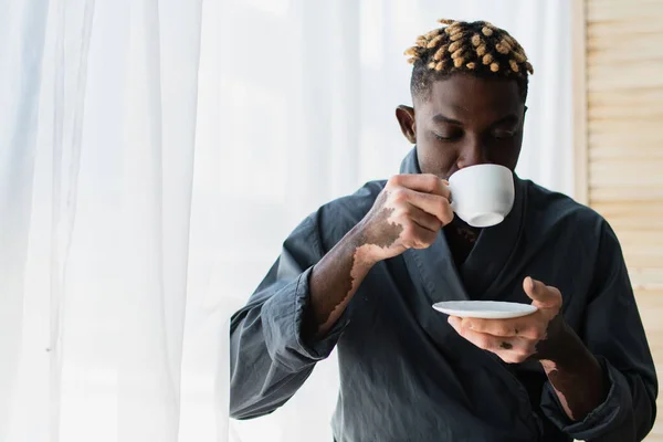 Young african american man with vitiligo drinking coffee at home in morning — Stock Photo