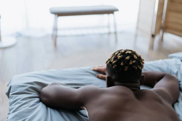 Back view of shirtless african american man with vitiligo lying on bed — Stock Photo