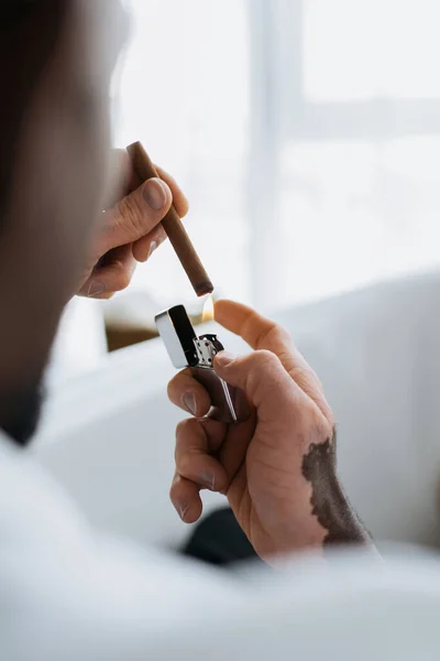 Unscharfe afrikanisch-amerikanische Mann mit Vitiligo hält Zigarre und Feuerzeug in Badewanne — Stockfoto