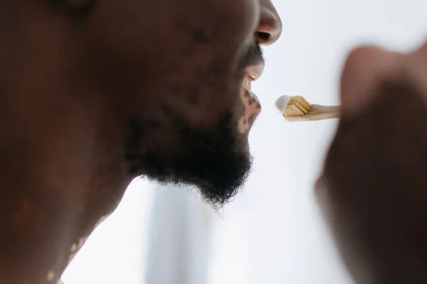 Vista recortada del hombre afroamericano con vitiligo cepillándose los dientes en casa - foto de stock