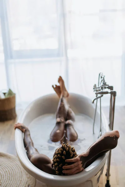 Visão traseira do homem americano africano com vitiligo tomando banho com espuma em casa — Fotografia de Stock