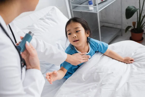 Curious asian girl with outstretched hand reaching doctor with inhaler in hospital — Stock Photo