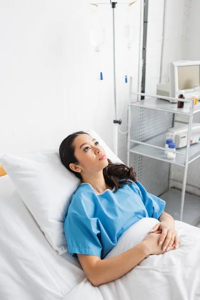 Blick aus der Vogelperspektive auf kranke und gestresste Asiatinnen, die auf dem Krankenhausbett liegen und wegschauen — Stockfoto