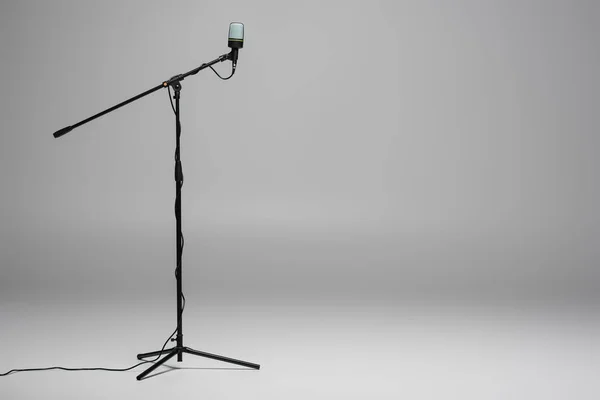 Black microphone with wire on metal stand on grey background with copy space — Stock Photo