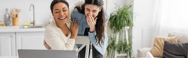 Lesbian multiracial woman with engagement ring on finger laughing with girlfriend during video call, banner — Stock Photo