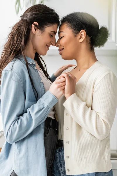 Side view of multiracial woman with engagement ring on finger holding hands with girlfriend — Stock Photo