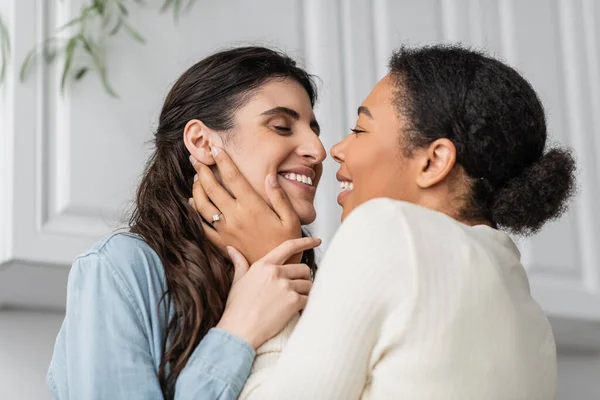 Überglückliche multirassische Frau mit Verlobungsring am Finger umarmt lächelnde Freundin — Stockfoto