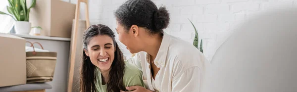Happy interracial lgbt couple laughing in new house, banner — Stock Photo