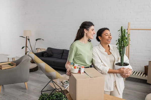 Cheerful interracial lgbt couple smiling while moving into new house — Stock Photo
