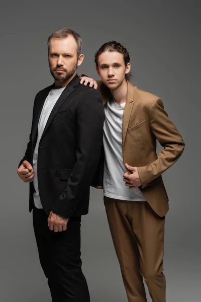 Gut gekleideter Vater und Teenager-Sohn in Anzügen, die isoliert auf grau stehen — Stockfoto