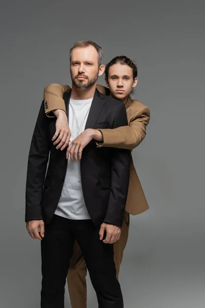 Gut gekleideter Teenager umarmt Vater im Anzug isoliert auf grau — Stockfoto