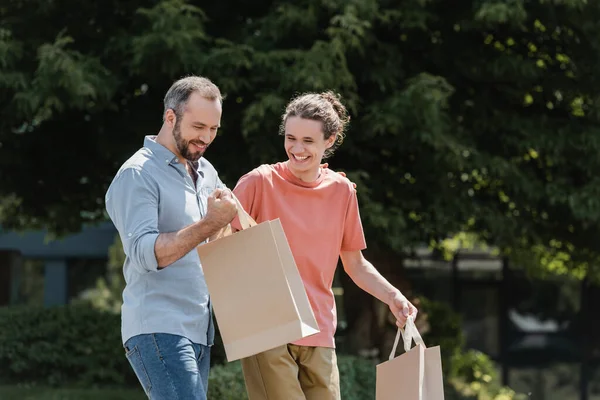 Fröhlicher Vater und Sohn spazieren mit Einkaufstüten im Freien — Stockfoto