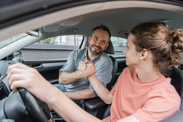 Happy father and son shaking hands while sitting together in car — Stock Photo