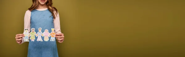 Обрезанный вид улыбающегося подростка в джинсовом сарафане с нарисованными бумажными персонажами во время всемирной защиты детей день на фоне хаки, баннер — стоковое фото