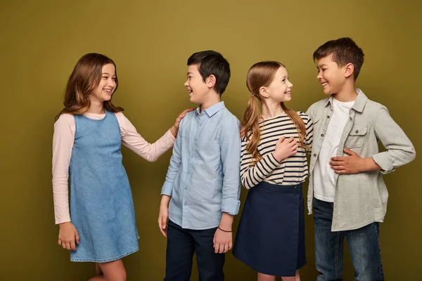 Smiling interracial and preteen kids in casual clothes talking to each other while celebrating international child protection day on khaki background — Stock Photo