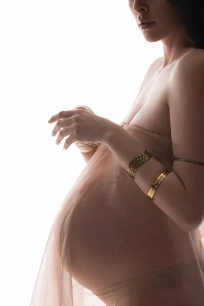 Vue partielle de la mère enceinte élégante en accessoires dorés et drapé en mousseline transparente isolé sur fond blanc, concept de mode maternité, attente, femme avec ventre — Photo de stock
