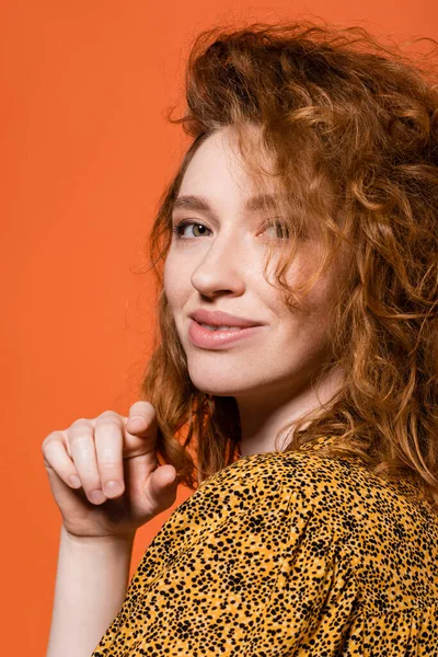 Portrait of young red haired model in yellow blouse with abstract print looking at camera and standing isolated on orange, stylish casual outfit and summer vibes concept, Youth Culture — Stock Photo