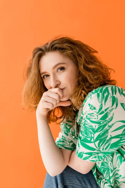 Portrait of young redhead woman with no-makeup look wearing modern blouse with floral print and jeans while looking at camera isolated on orange, trendy casual summer outfit concept, Youth Culture — Stock Photo