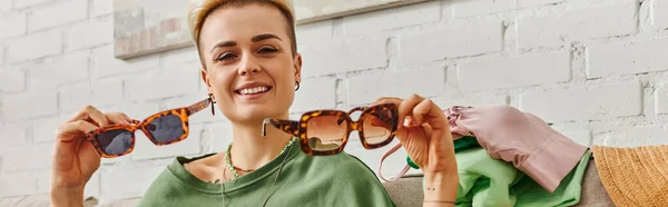Happy emotion, cheerful tattooed woman with trendy hairstyle showing fashionable sunglasses and looking at camera, sustainable living and mindful consumerism concept, banner — Stock Photo