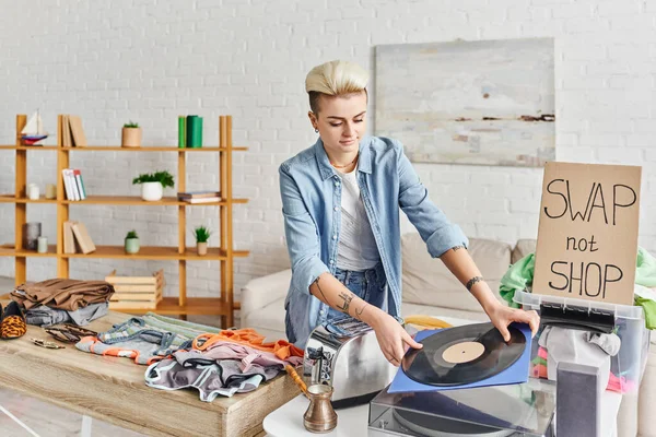 Collaborative consumption, smiling tattooed woman holding vinyl disc near record player, electric toaster, cezve, clothes and swap not shop card, sustainable living and circular economy concept — Stock Photo