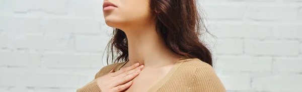 Cropped view of young brunette woman in jumper touching neck during self-massage of lymphatic system at home, self-care ritual and holistic wellness practices concept, banner, tension relief — Photo de stock