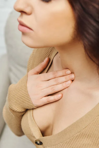 Cropped view of young woman in casual jumper touching neck during self-massage for circulation and lymphatic drainage at home, self-care ritual and holistic wellness practices concept — Photo de stock