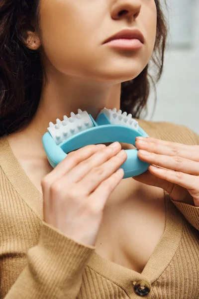 Cropped view of young woman in brown jumper doing self-massage of lymphatic system and nodes with handled massager at home, enhancing self-awareness and body relaxation concept, balancing energy — Stock Photo