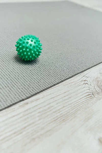 Close up view of handle massage ball lying on fitness mat on floor at home, natural health practices and home-based massage concept, health and relaxation, beauty and wellness routine — Stock Photo