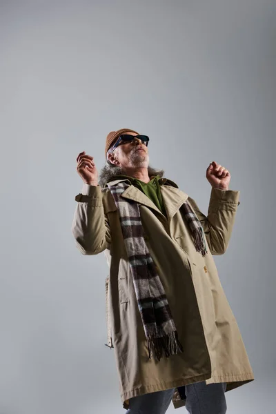 Ausdrucksstarke Persönlichkeit, älterer und bärtiger Hipster mit dunkler Sonnenbrille und stylischem lässigem Outfit auf grauem Hintergrund, modisches und positives Lifestylekonzept — Stockfoto