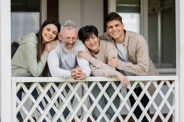 Parents day, middle aged parents hugging with teenage daughter and young adult son on porch of family house, celebration, bonding, modern parenting, moments to remember, laughter — Stock Photo