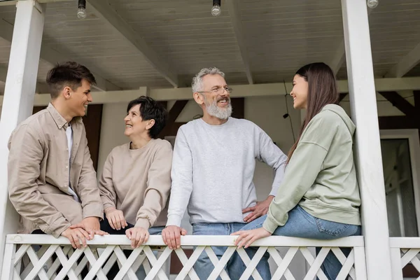 Parents day, middle aged parents chatting with teenage daughter and young adult son on porch of summer house, family celebration, bonding, moments to remember, modern parenting — Stock Photo