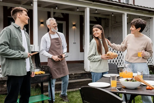 Happy parents day, family and food, cheerful middle aged parents, daughter and son, family bbq party in summer house, suburban, weekend, bonding and modern parenting, barbecue — Stock Photo