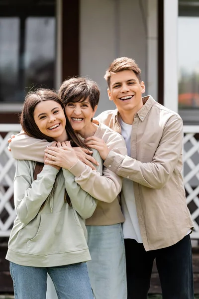 Family photo, happy parents day, cheerful teenage girl and young adult son hugging mother on backyard of summer house, family celebration, bonding, moments to remember, modern parenting — Stock Photo
