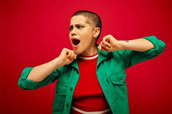 Emotional, bold makeup, generation z, youth culture, shocked young woman with short hair posing with opened mouth on red background, youth culture, vibrant background, stylish appearance — Stock Photo