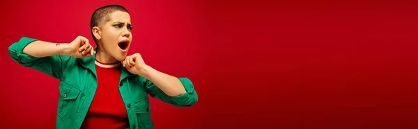 Emotional, bold makeup, generation z, youth culture, shocked young woman with short hair posing with opened mouth on red background, youth culture, vibrant background, stylish appearance, banner — Stock Photo