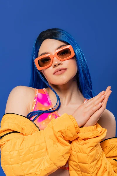Mode-Statement, junges weibliches Model mit blauen Haaren und trendiger Sonnenbrille auf blauem Hintergrund, Generation Z, Rebellentyp, bunte Kleidung, Individualismus, moderne Frau, die in die Kamera schaut — Stockfoto