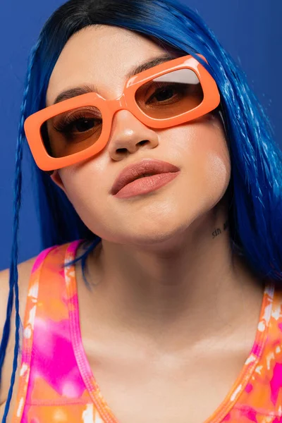 Портрет, модный аксессуар, молодая женщина модель с голубыми волосами и модные солнцезащитные очки изолированы на голубом фоне, поколение z, повстанческий стиль, стиль повстанцев, индивидуализм, современная женщина — стоковое фото
