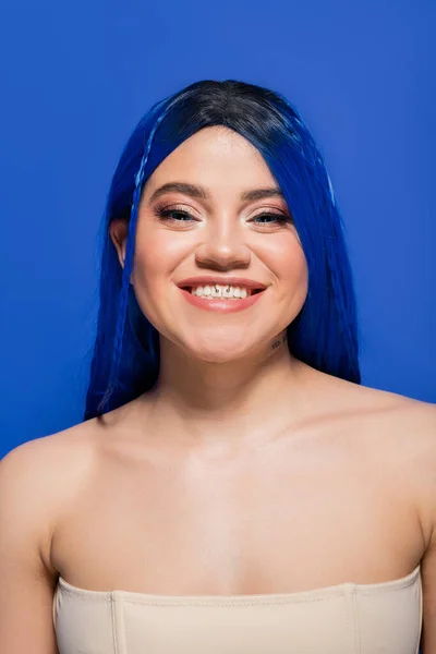 Красиві тенденції, щаслива молода жінка з фарбованим волоссям позує на синьому фоні, колір волосся, індивідуалізм, жіноча модель з макіяжем і модною зачіскою, яскрава молодь, досконалість шкіри, татуювання — стокове фото