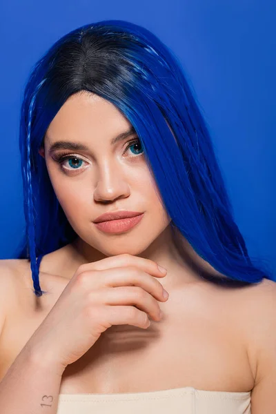 Concept tendances beauté, jeune femme aux cheveux teints posant sur fond bleu, couleur de cheveux, individualisme, modèle féminin avec maquillage et coiffure tendance, jeunesse vibrante, perfection de la peau — Photo de stock