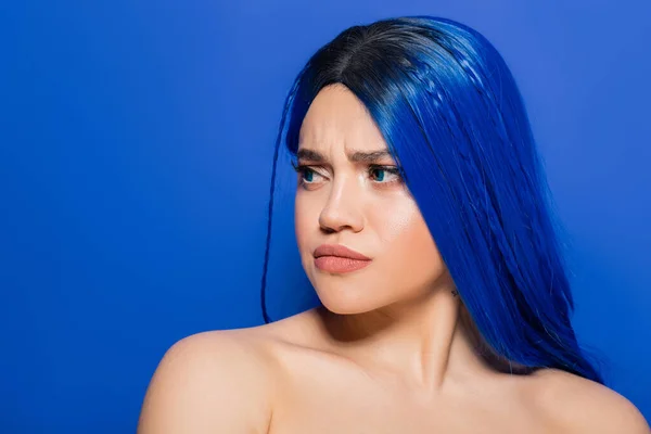 Retrato de mujer insatisfecha con el pelo teñido mirando hacia otro lado sobre fondo azul, color de pelo, individualismo, modelo femenino con maquillaje y peinado de moda, juventud vibrante, emocional - foto de stock