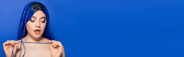 Vibrante gioventù, espressione di sé, emotivo, ritratto di giovane donna con i capelli tinti in posa su sfondo blu, colore dei capelli, individualismo, modello femminile con trucco e acconciatura alla moda, banner — Foto stock
